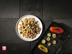 Pennes de blé entier aux légumes grillés : olives Kalamata, aubergines sur le grill, poivrons aux couleurs de l’arc-en-ciel, jolies courgettes, le tout nappé de fromage féta et d’une sauce fraiche aux tomates californiennes garnie d’un pesto maison au basilic du jardin